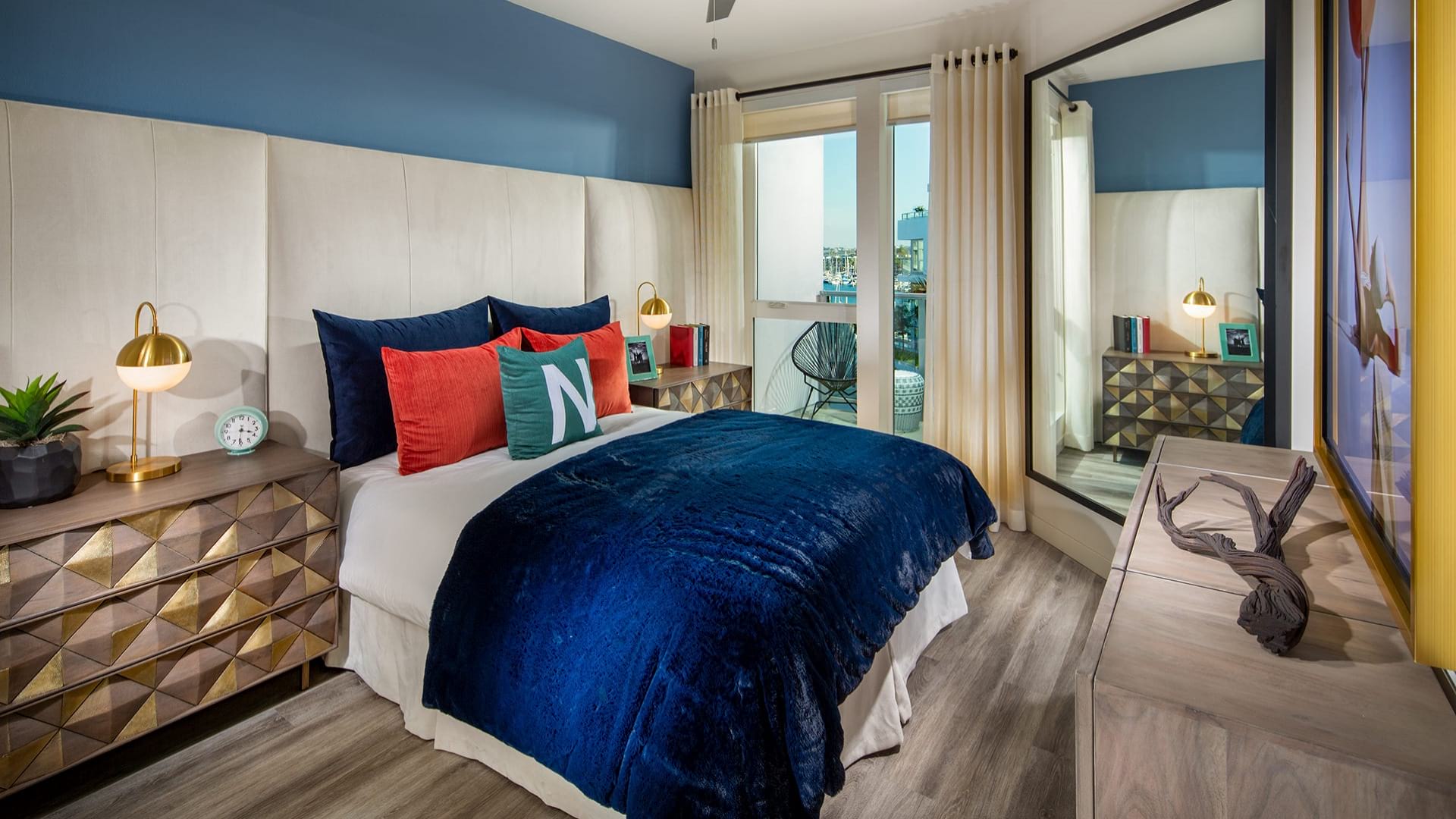 Large apartment bedroom with a bed, bedside table, and door to a private balcony