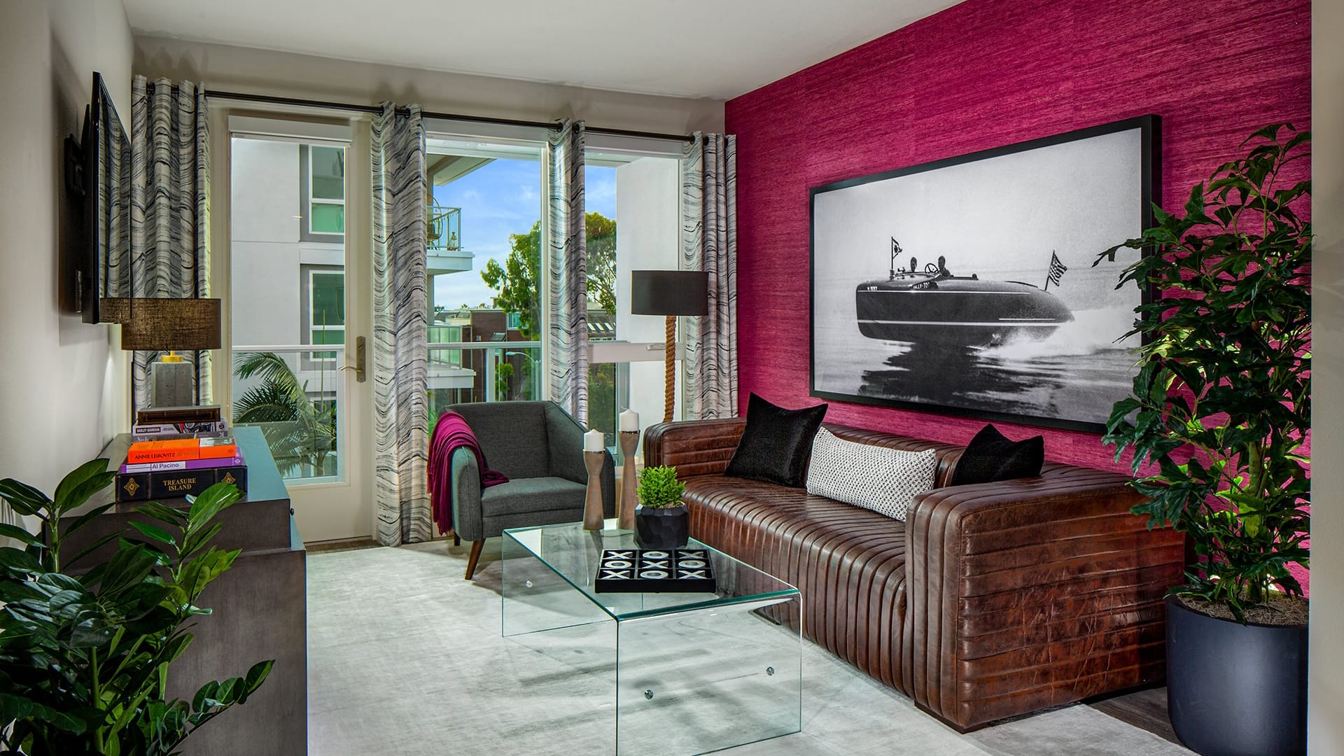Spacious living room in an apartment with a leather couch, glass coffee table, and a balcony overlooking Marina del Rey