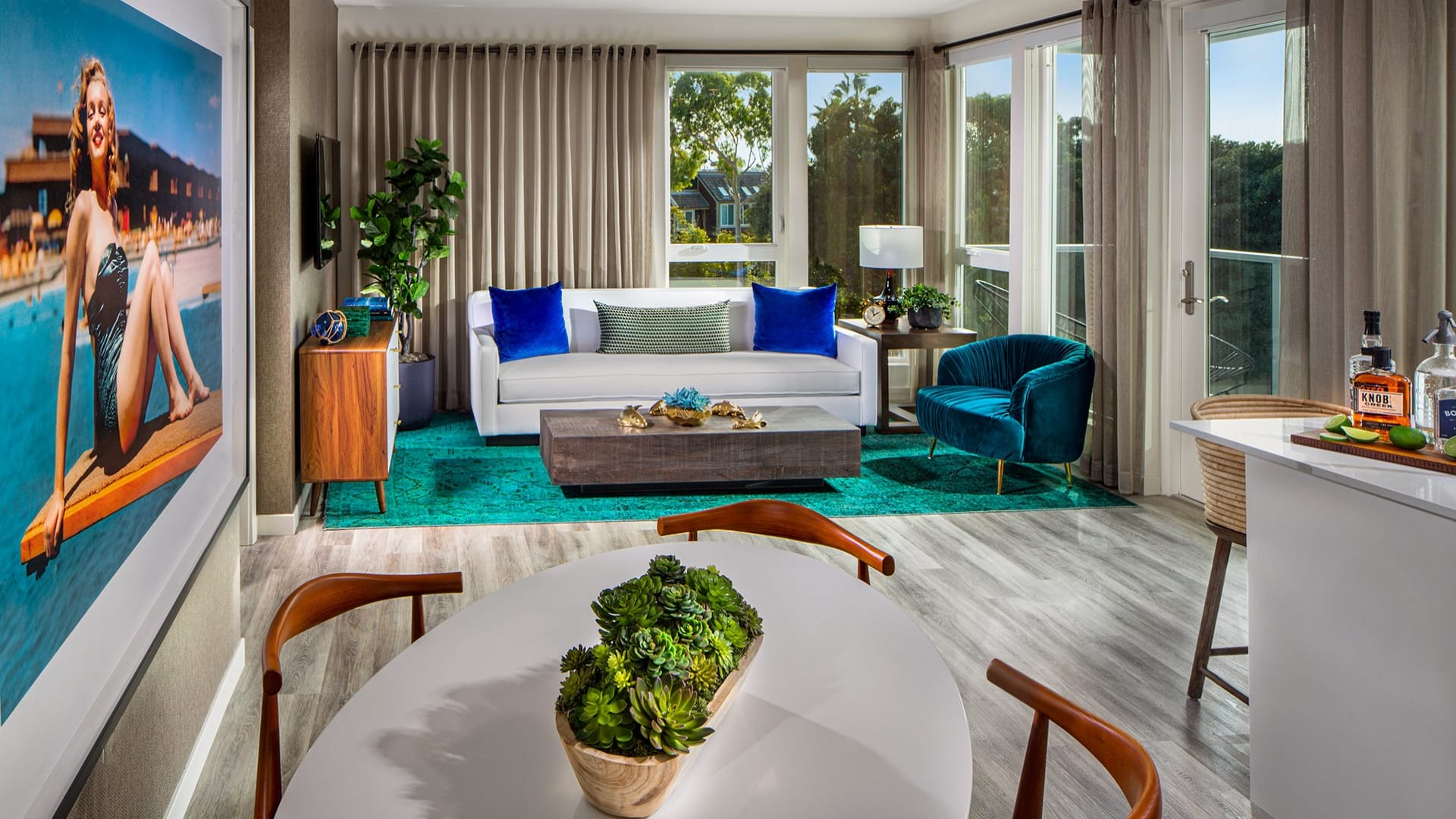 Living room featuring a white couch and blue chair surrounded by floor to ceiling windows. 